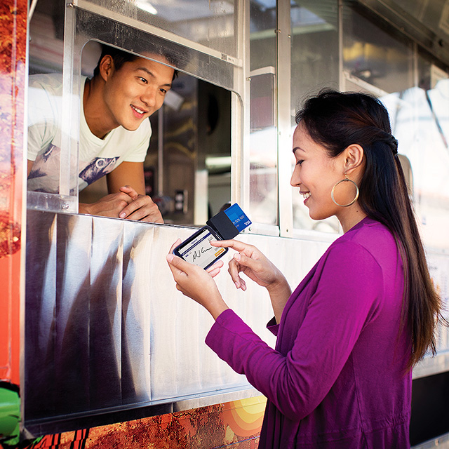 Woman using a mobile card reader to pay at a food truck